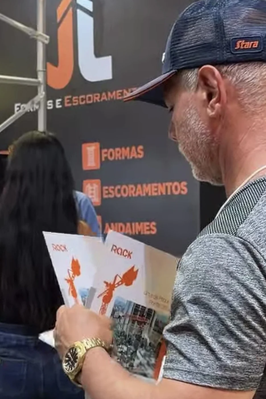 Visitante consulta material de produtos em um estande.